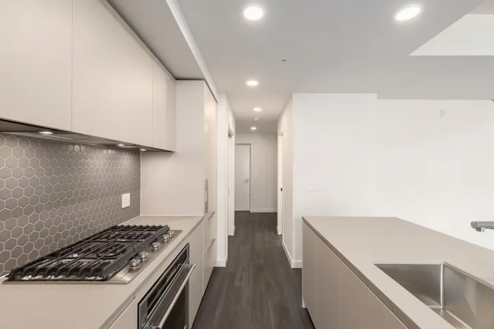 Modern kitchen featuring a gas range, integrated oven, hexagon tile backsplash, contemporary cabinetry, and an undermount sink on an island