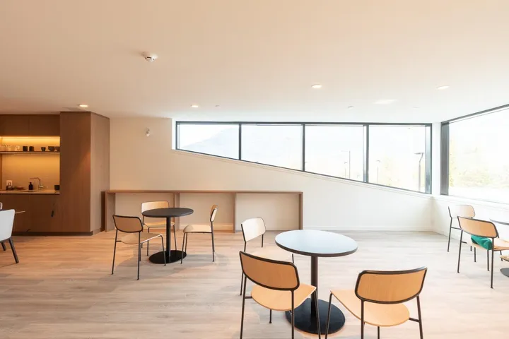 Large-format angular windows with black framing, integrated cabinetry with built-in shelving, recessed ceiling lighting, and wood-finish flooring