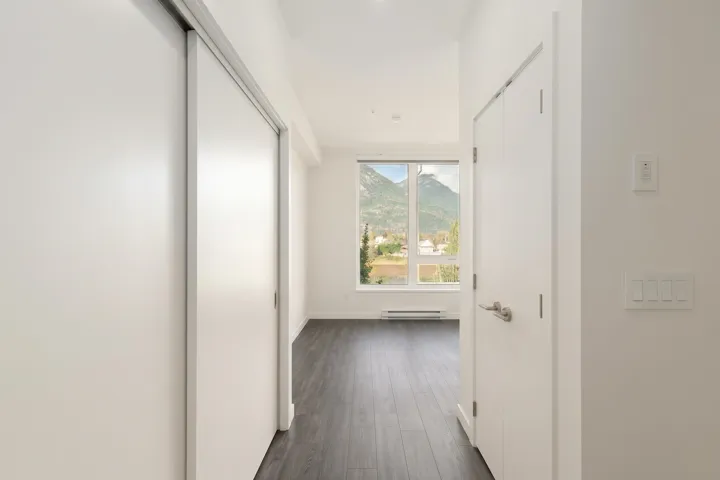 Dark-toned wood-finish flooring, floor-to-ceiling window with mountain backdrop, sliding closet doors, and interior hinged door with satin nickel hardware