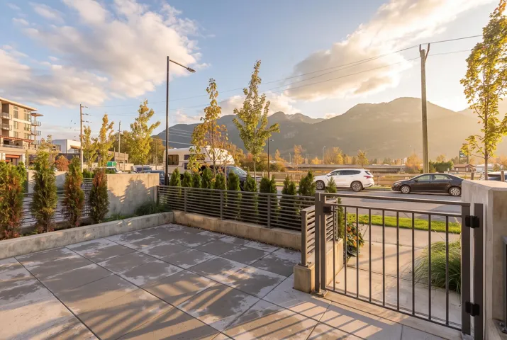 Paved patio featuring concrete hardscaping, metal perimeter fencing, a gated entry, and mountain scenery