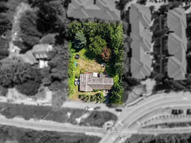 Expansive property featuring a shingle-roof residence, mature trees, and a spacious green area