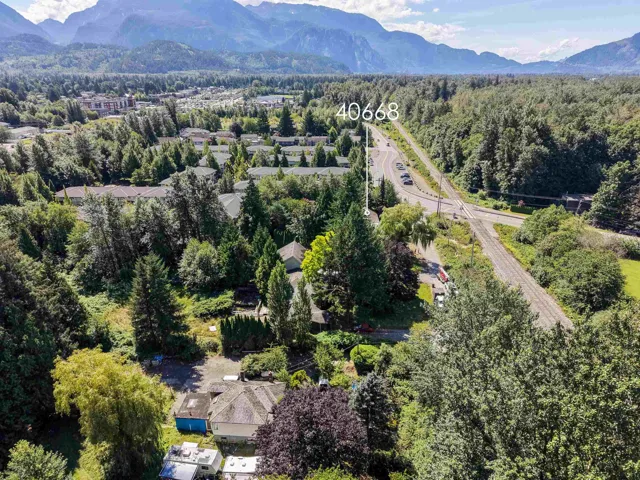 Expansive property featuring mature trees, residential structures, and a clear view of mountain ranges