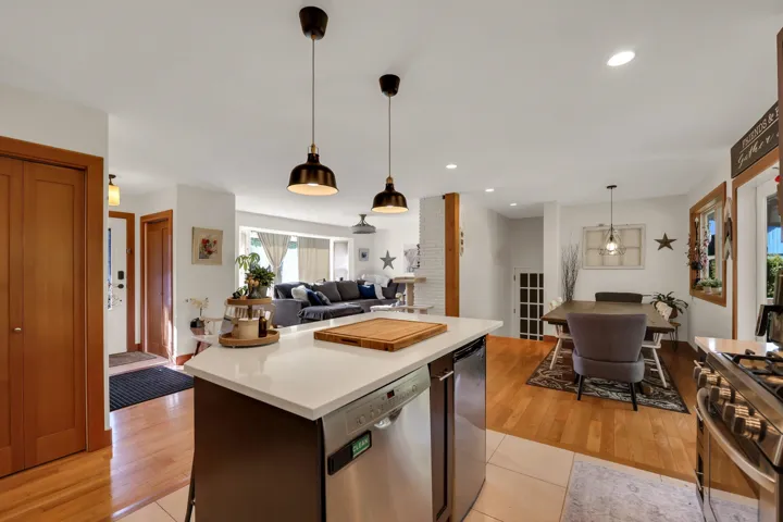 Kitchen with light countertops, stainless steel appliances, open floor plan, a kitchen island, and decorative light fixtures