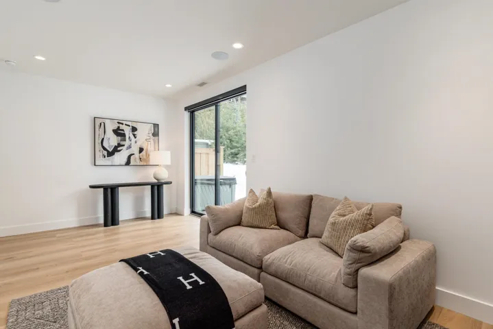 Media room featuring light wood-style flooring, recessed lighting, custom media unit, and access to back patio.