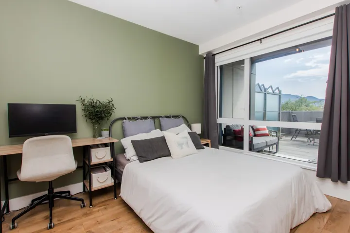 Bedroom with light wood-style flooring, access to outside, and a desk