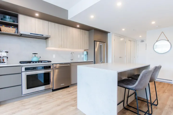 Kitchen with stainless steel appliances, a breakfast bar, open shelves, modern cabinets, and light wood-type flooring