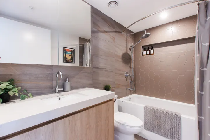 Full bath with tile walls, shower / bathtub combination with curtain, vanity, and backsplash