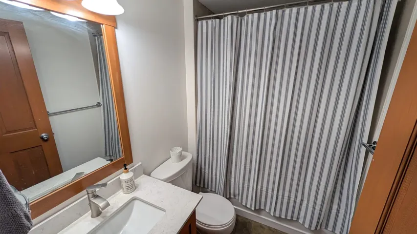 Bathroom with wood-framed mirror, contemporary vanity with white countertop, integrated sink, and brushed nickel faucet