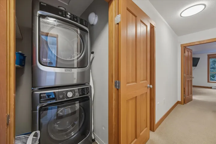 Laundry area featuring stacked washer and clothes dryer and carpet floors