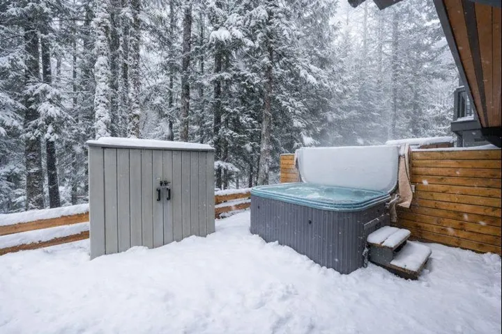 Yard covered in snow with a hot tub and a shed