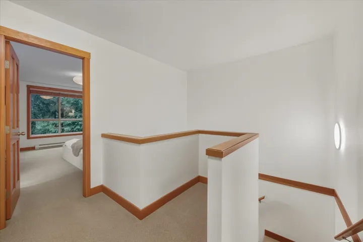 Hall with an upstairs landing, carpet flooring, and a baseboard radiator