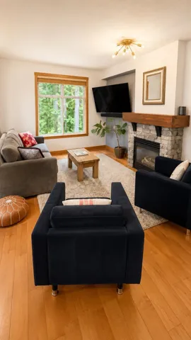 Living area featuring wood-finish flooring and a stone-faced fireplace with a wood mantel