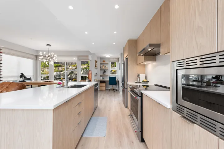 Kitchen featuring appliances with stainless steel finishes, light brown cabinetry, modern cabinets, range hood, and light wood-style flooring
