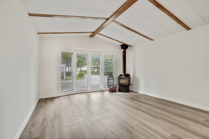 Unfurnished living room with a wood stove and light wood-style flooring