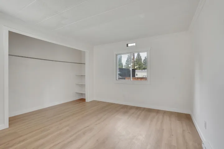 Unfurnished bedroom with light wood-style flooring, ornamental molding, a closet, and a baseboard heating unit