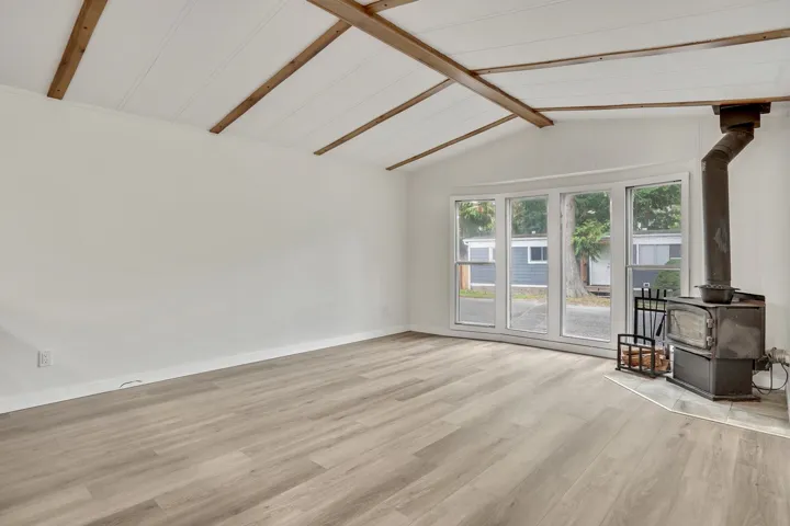 Unfurnished living room featuring a wood stove and light wood-style flooring