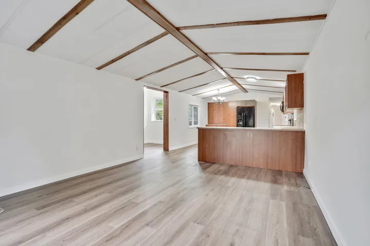 Kitchen with a peninsula, light countertops, light wood-style floors, brown cabinetry, and a chandelier