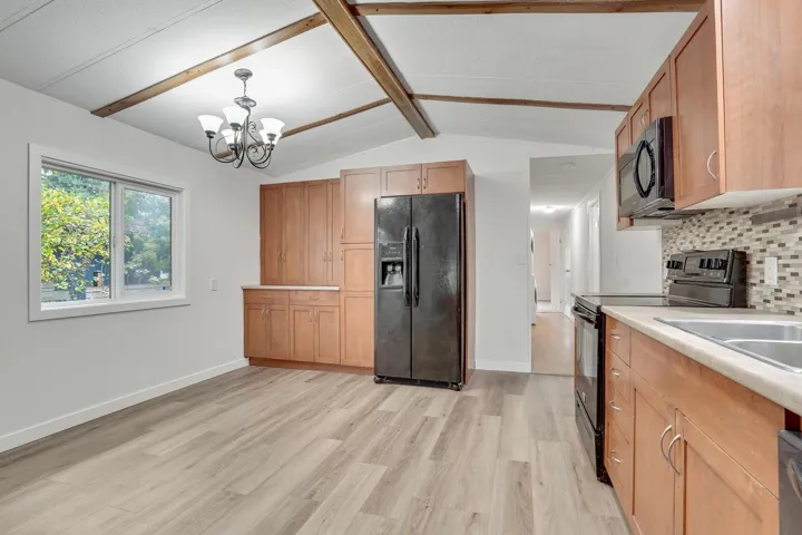 Kitchen with black appliances, tasteful backsplash, light wood-style flooring, light countertops, and hanging light fixtures