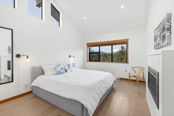 Bedroom with high vaulted ceiling, a fireplace, wood-type flooring, and baseboards