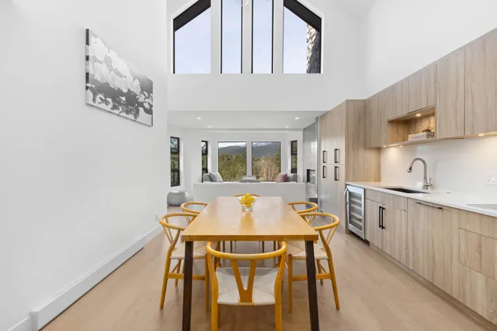 Dining space with light wood-type flooring, recessed lighting, a high ceiling, beverage cooler, and baseboards