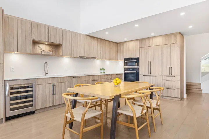 Kitchen featuring modern cabinets, light wood-type flooring, light brown cabinetry, a sink, and beverage cooler