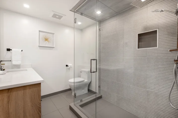 Full bath featuring tiled shower, vanity, tile patterned flooring, toilet, and baseboards