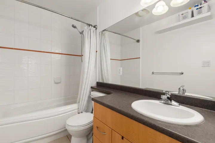 Bathroom featuring a wood-finish vanity with a dark countertop and integrated oval sink