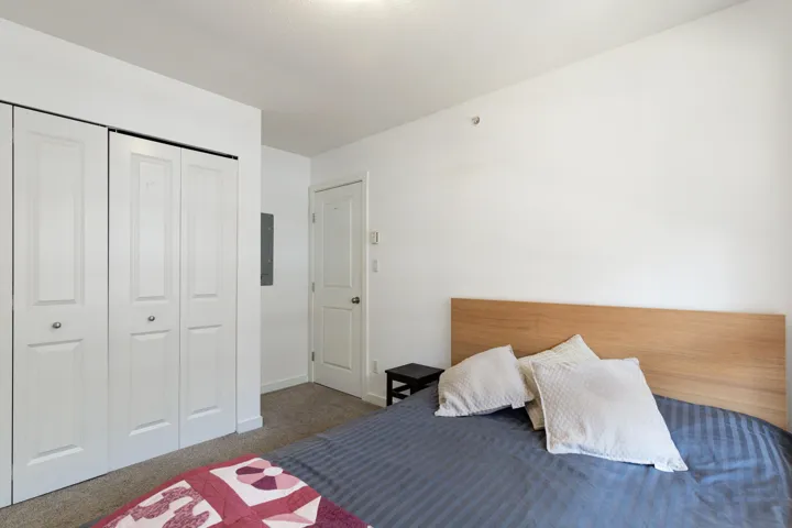 Bedroom featuring light carpet flooring, white walls, and a flat white ceiling