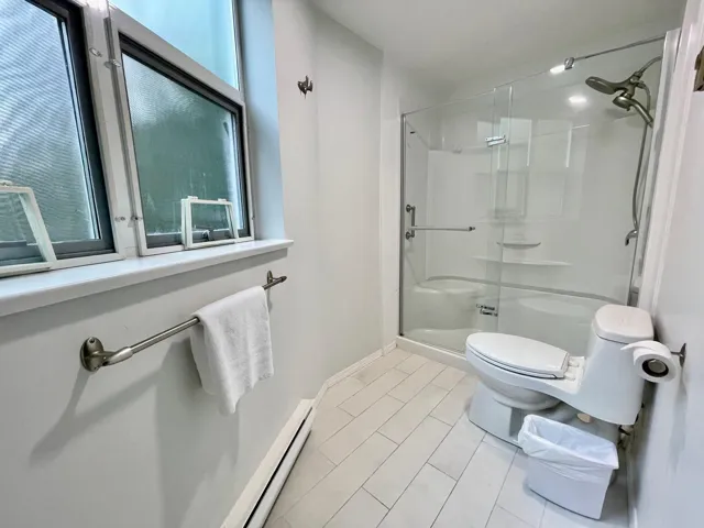 Bathroom with a stall shower, baseboard heating, and tile patterned flooring
