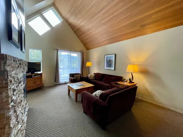 Carpeted living area featuring high vaulted ceiling, plenty of natural light, and wooden ceiling