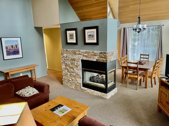 Living area featuring a chandelier, carpet flooring, lofted ceiling, wood ceiling, and a stone fireplace