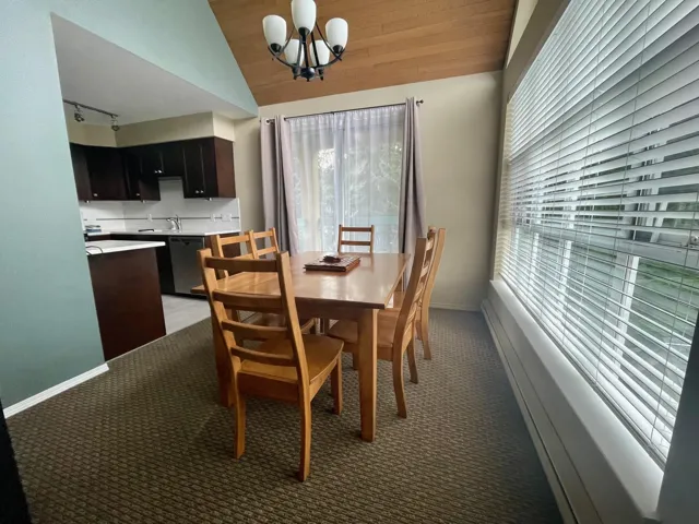 Dining room with light carpet, a chandelier, vaulted ceiling, and track lighting