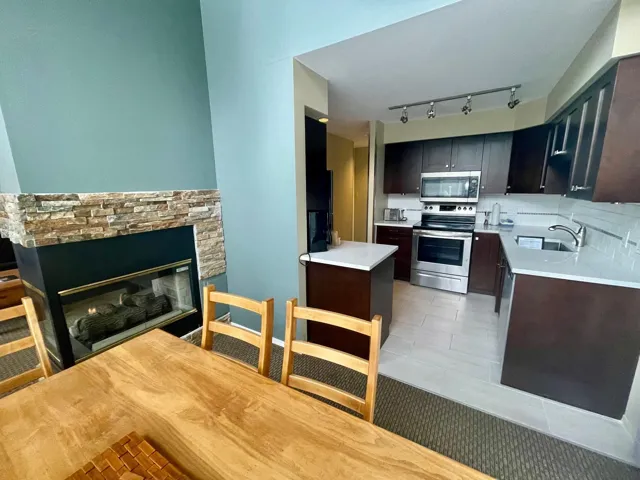 Kitchen with appliances with stainless steel finishes, a fireplace, light countertops, and tasteful backsplash