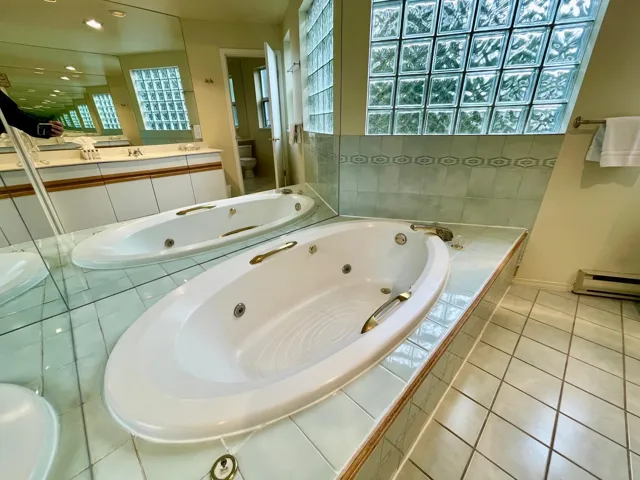 Bathroom with a tub with jets, vanity, baseboard heating, plenty of natural light, and recessed lighting