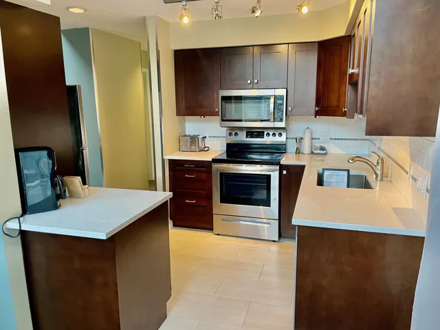 Kitchen with appliances with stainless steel finishes, tasteful backsplash, dark brown cabinetry, and light tile patterned floors