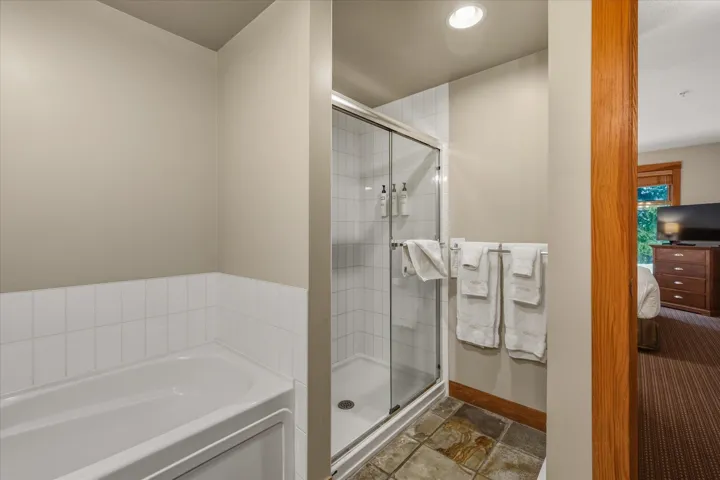 Bathroom featuring ensuite bathroom, a bath, stone tile floors, a stall shower, and recessed lighting