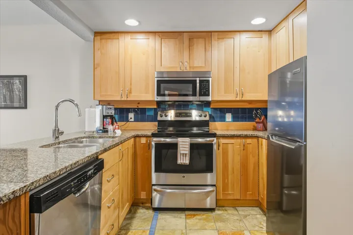 Kitchen with stainless steel appliances, dark stone countertops, tasteful backsplash, and recessed lighting