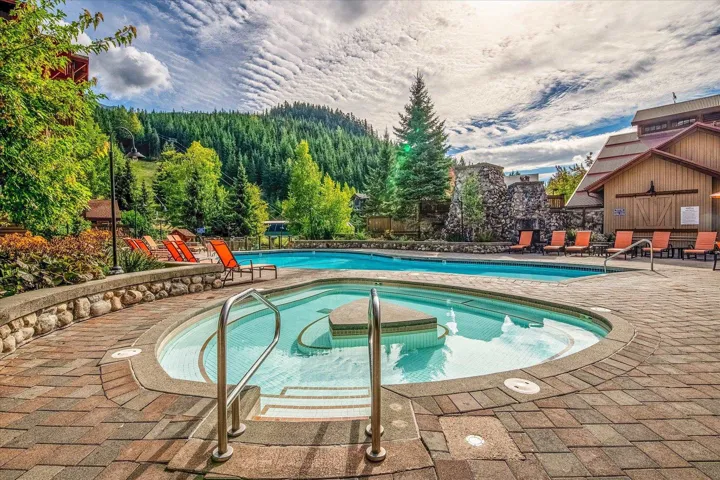 Community pool with a patio area and a hot tub