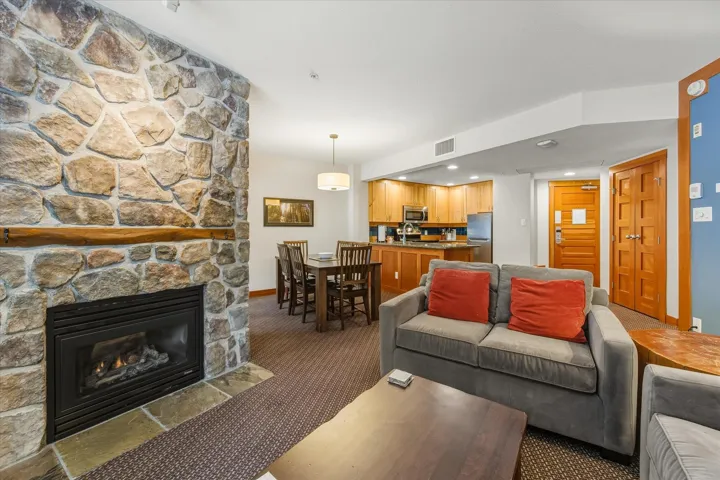 Carpeted living room with a stone fireplace and recessed lighting