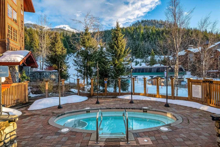 Snow covered pool with a hot tub, a patio, a mountain view, and a pool
