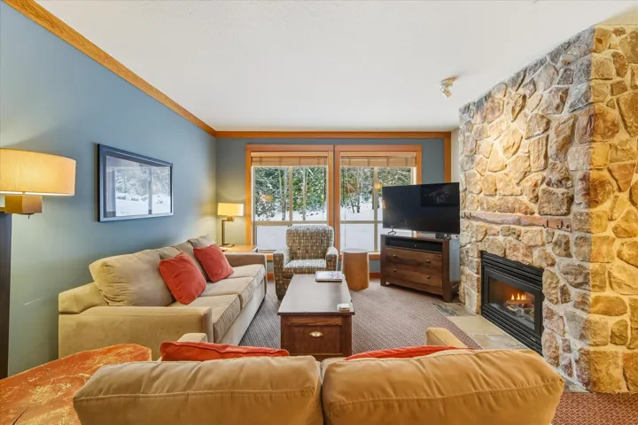 Carpeted living area with a stone fireplace and a textured ceiling