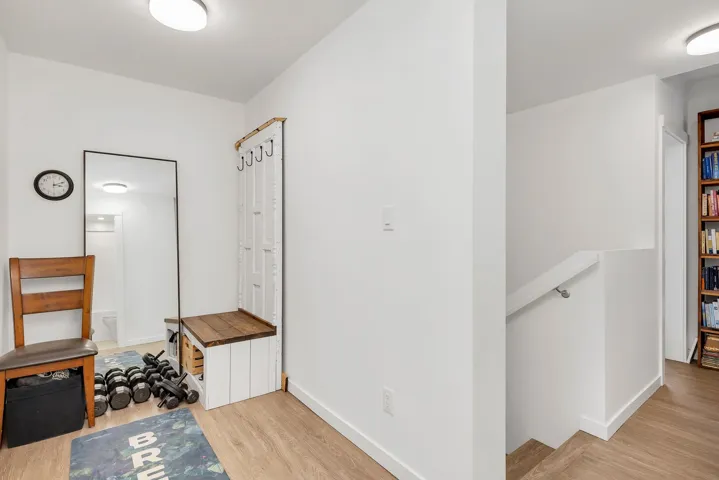Hallway with light wood-style floors and an upstairs landing