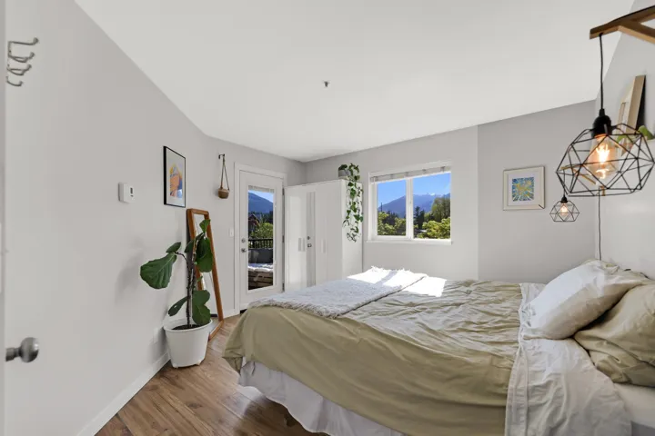 Bedroom featuring wood-finish flooring, a double window, and an exterior door leading to a balcony