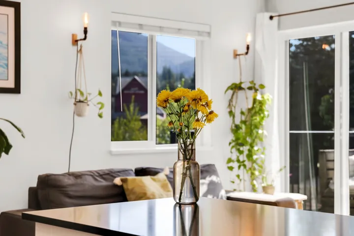 White interior wall with a wall-mounted light fixture and a window featuring a mountain backdrop