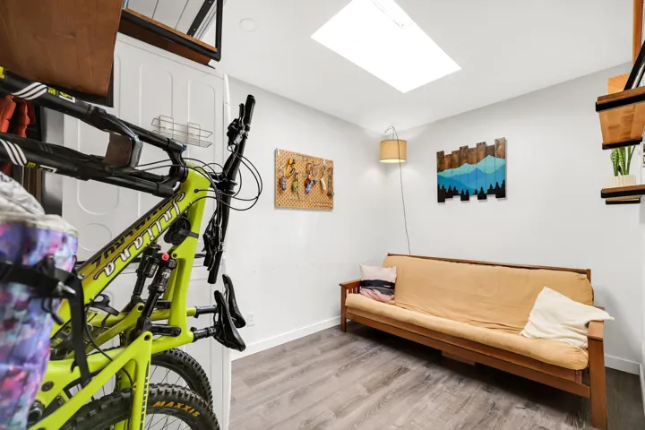 Versatile room featuring wood-finish flooring, a ceiling-mounted skylight, and white walls