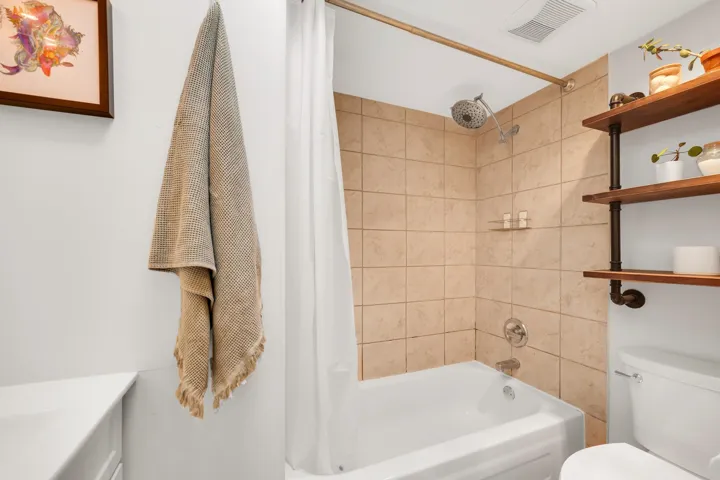 Full bathroom featuring a shower-tub combination with natural-toned tile surround
