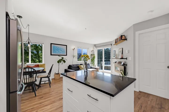 Open-concept living area featuring a kitchen island with dark countertop, wood-finish flooring, white paneled interior doors, and sliding glass doors leading to an exterior space