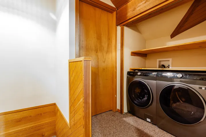 Clothes washing area featuring washer and clothes dryer and carpet floors