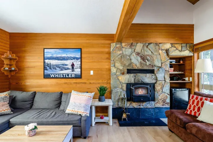 Living area with wooden walls, wood finished floors, beam ceiling, and a wood stove