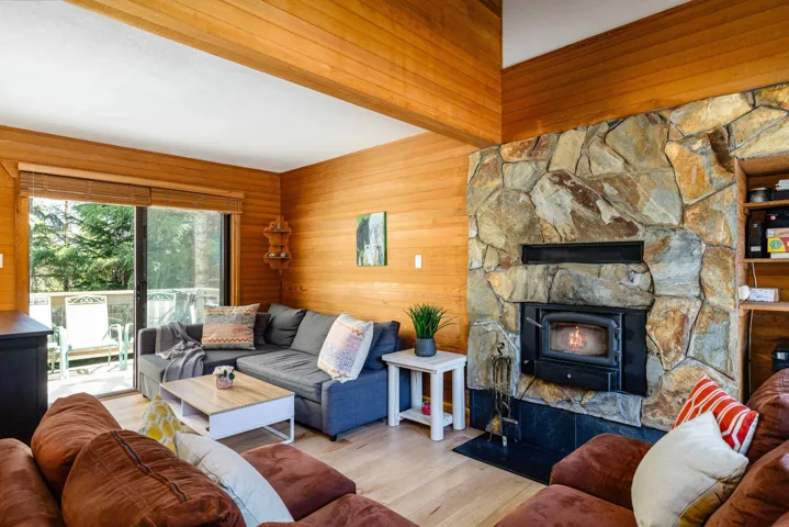 Living room with wood walls, wood finished floors, and a wood stove